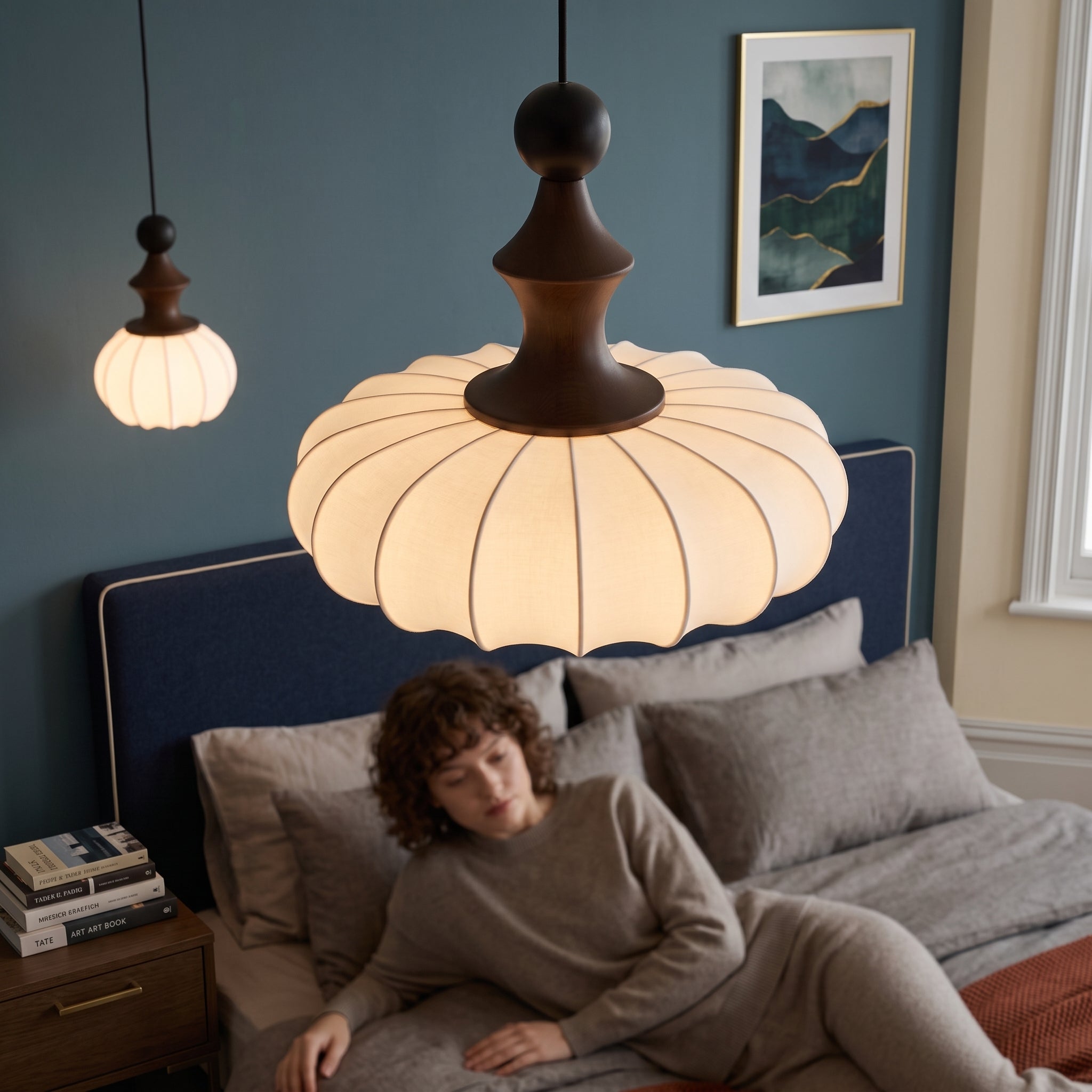 Qizlu silk lantern pendant light above a bed with a blue headboard