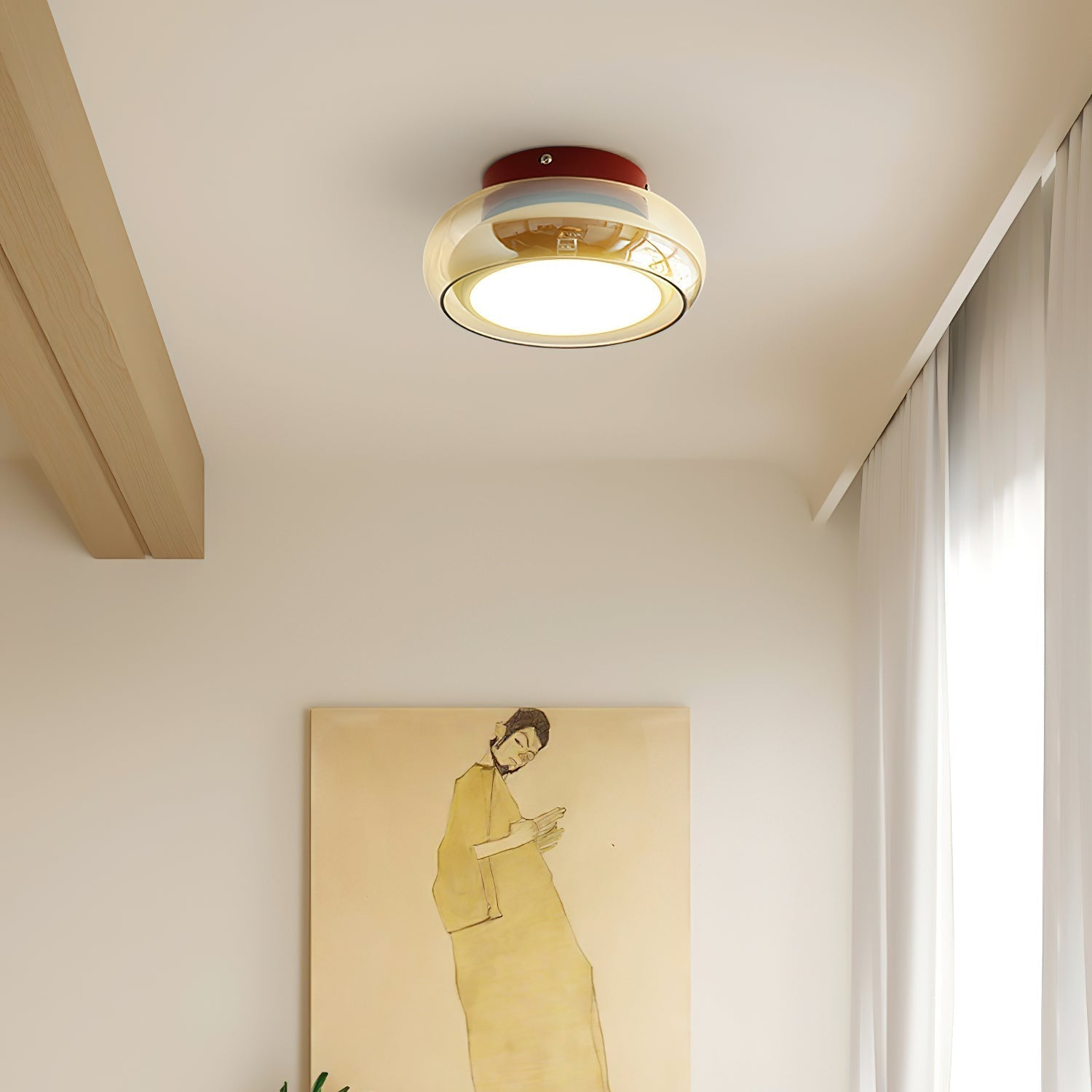 Red base and amber glass flush mount ceiling light providing ambient lighting above a painting