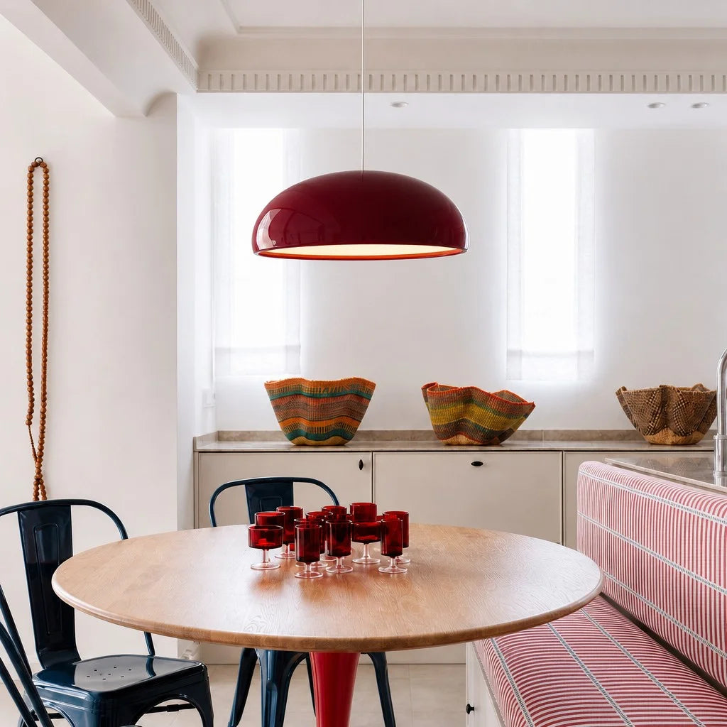 Red metal dome ceiling lamp illuminating a bright, contemporary open-plan kitchen and dining space