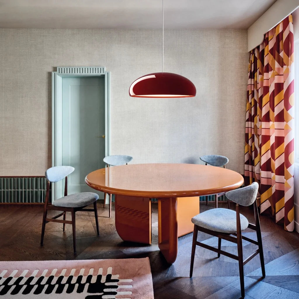 Minimalist red metal pendant light hanging elegantly above a round wooden table