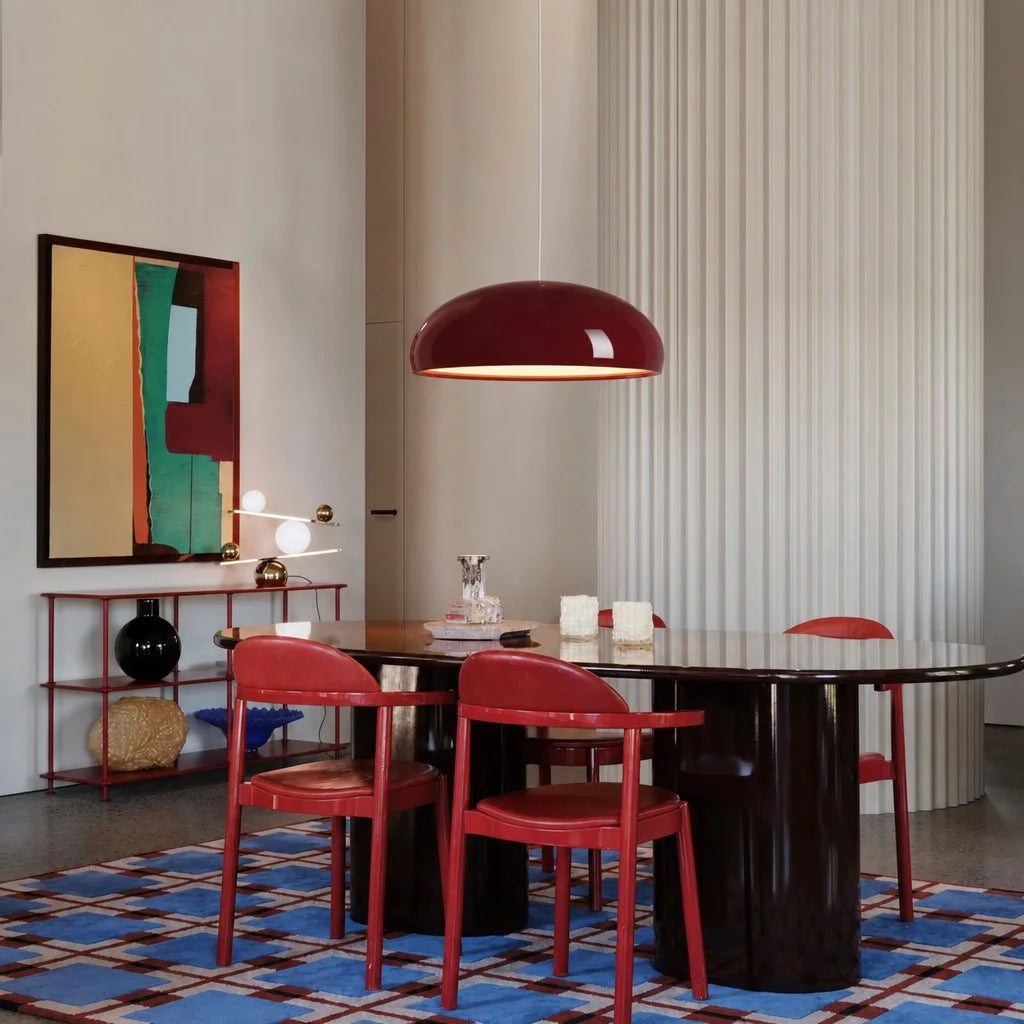 Red Nordic pendant light providing a warm glare-free glow over a dark dining table