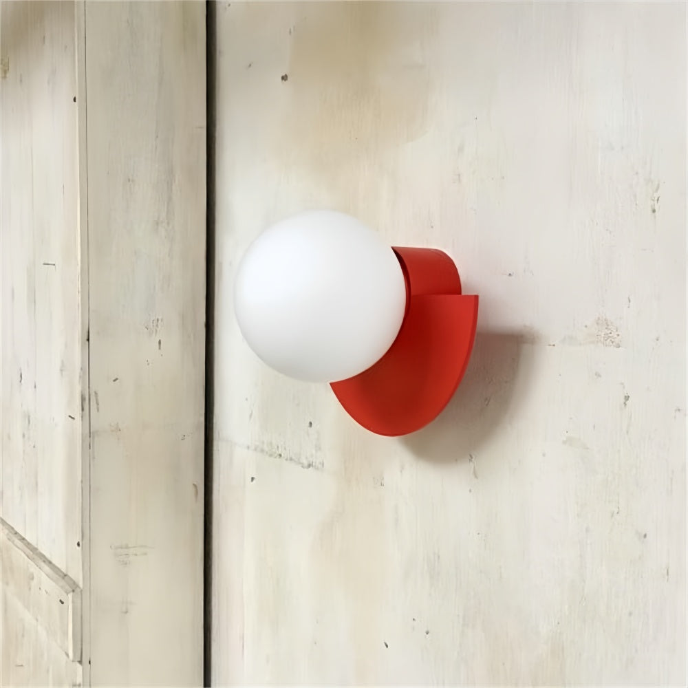 Vibrant red semi-circle globe wall sconce mounted on an industrial concrete wall