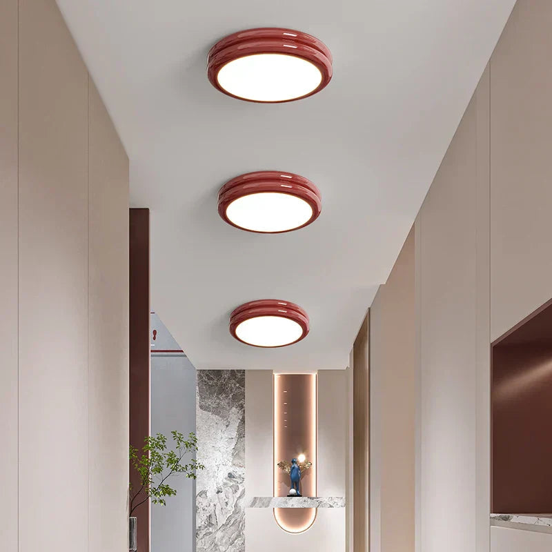 Three vibrant red stepped-ring flush mount lights arranged in a sequence down a long corridor