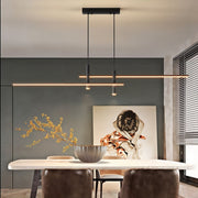 Modern rera matte black intersecting LED linear pendant light suspended above a contemporary dining table