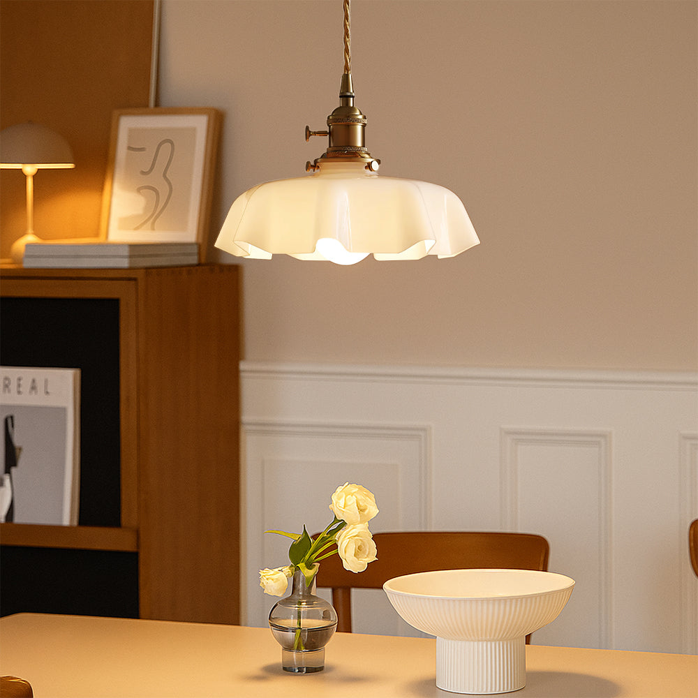 Retro brass and cream glass chandelier suspended over a minimalist dining table providing a warm ambient glow