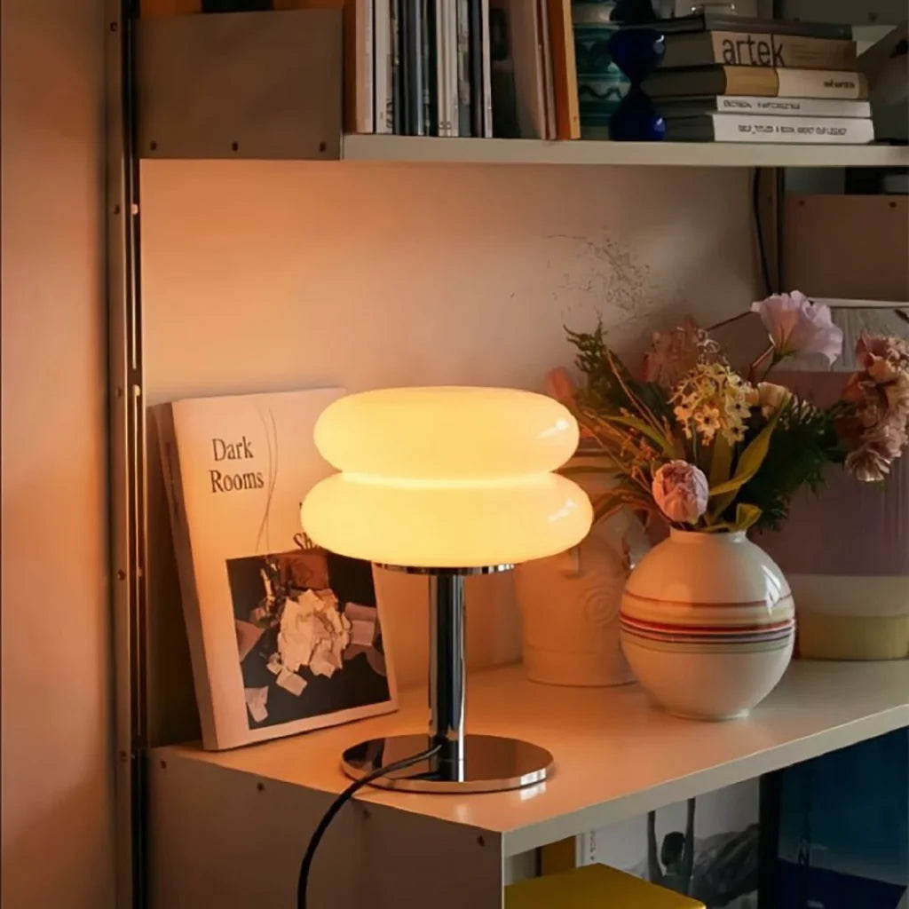 etro glass table lamp providing cosy, warm illumination on a styled bookshelf