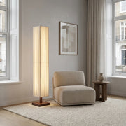 Ruxpa walnut wood Japanese floor lamp beside a beige armchair with cream curtains and a wood side table