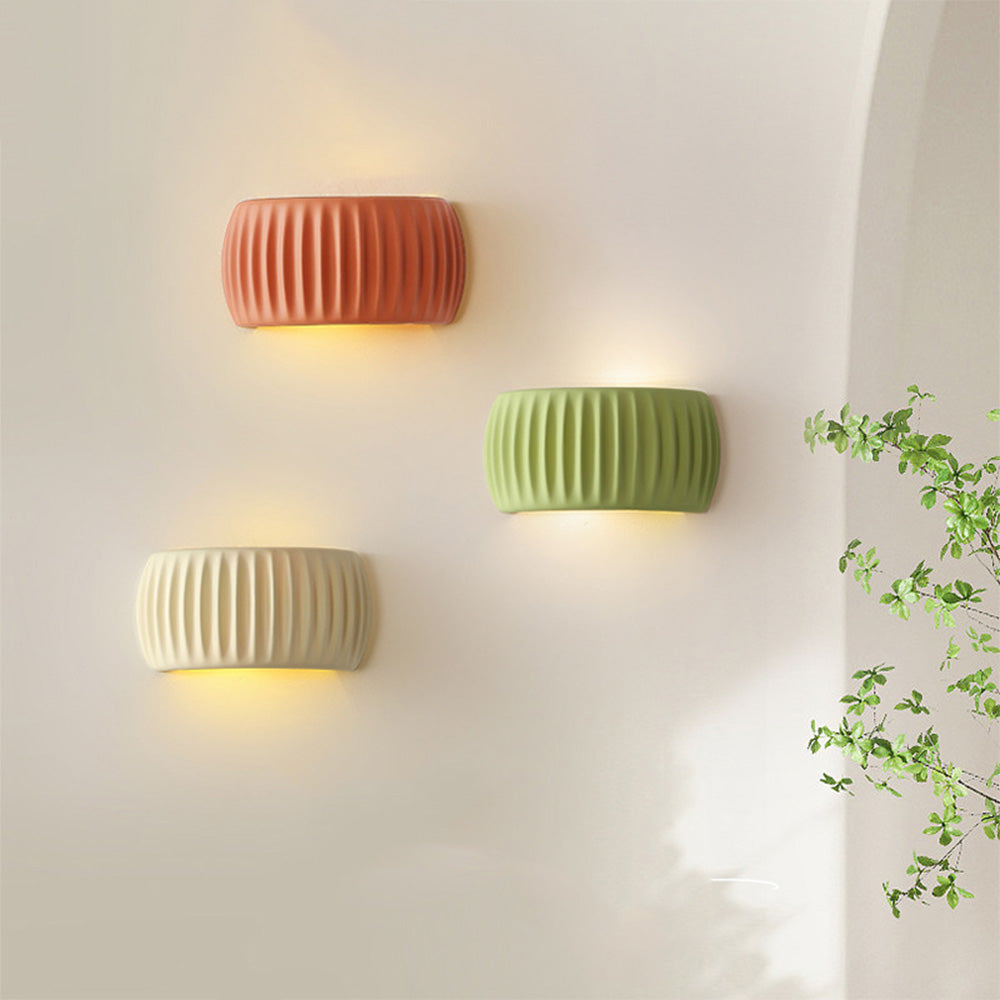 Three colourful ryfy Nordic resin wall sconces in orange, green, and white arranged on a modern wall