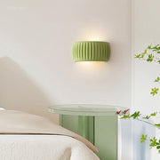 Modern ryfy green fluted resin wall sconce illuminating a contemporary bedroom bedside table