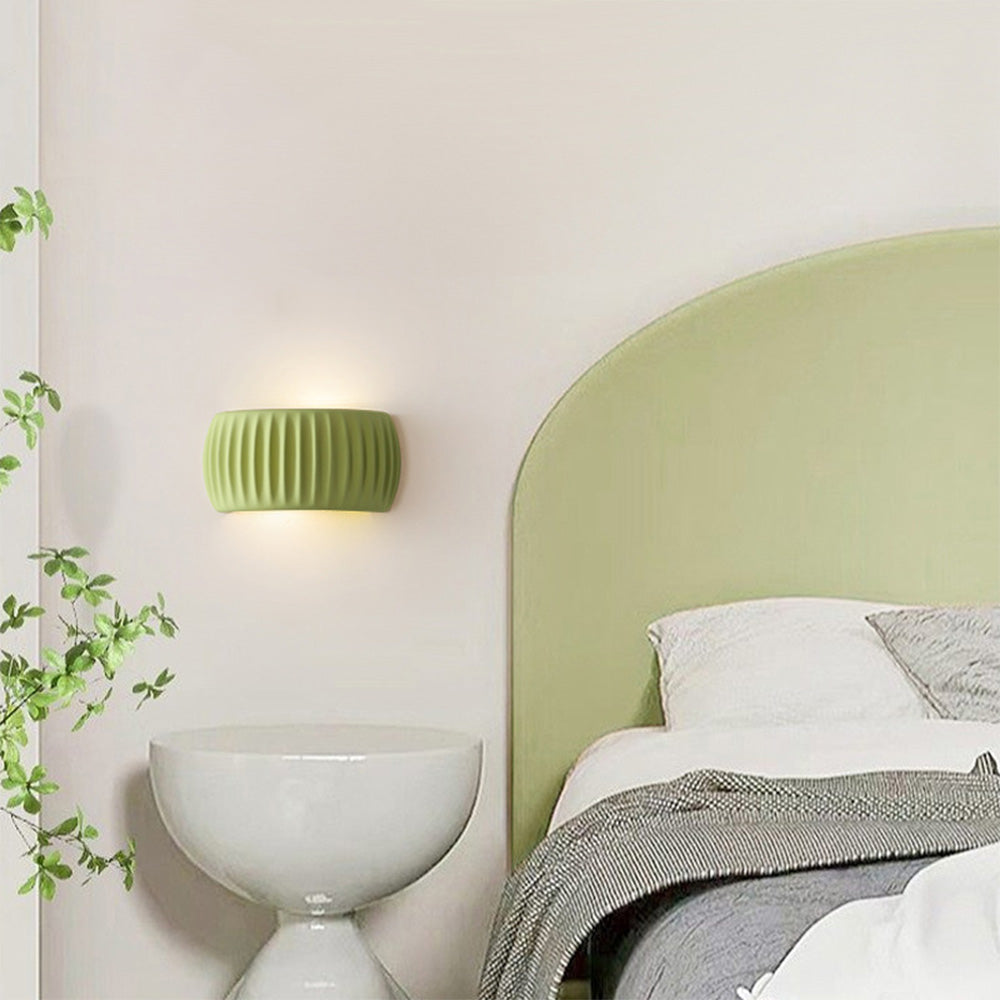 Green ryfy semi-circle fluted wall sconce providing warm ambient lighting above a bedroom headboard