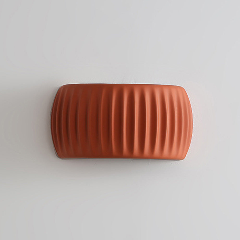Front ryfy view of the unlit orange ribbed resin wall light showcasing its textured matte finish