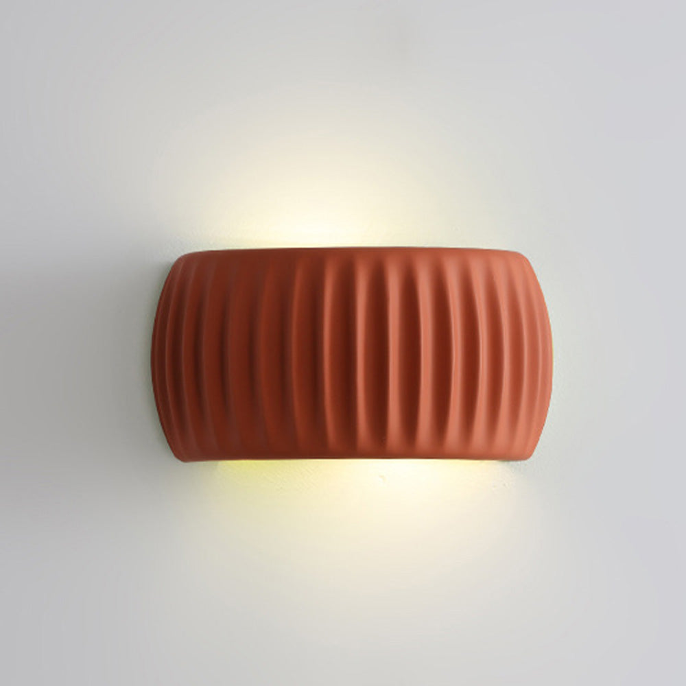 Illuminated ryfy orange up and down wall sconce casting a warm hourglass-shaped light beam