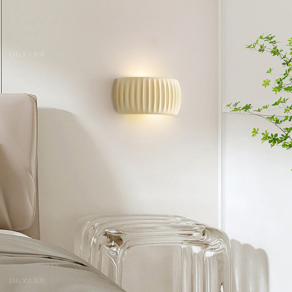 White ryfy fluted resin wall lamp acting as an elegant accent light in a bright, modern bedroom