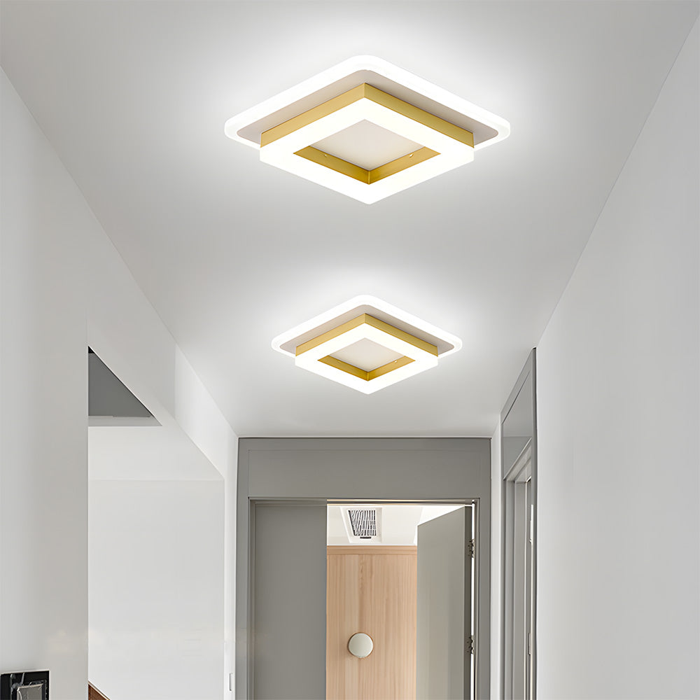 Pair of modern gold geometric square LED serq ceiling lamps installed in a bright, naturally lit corridor