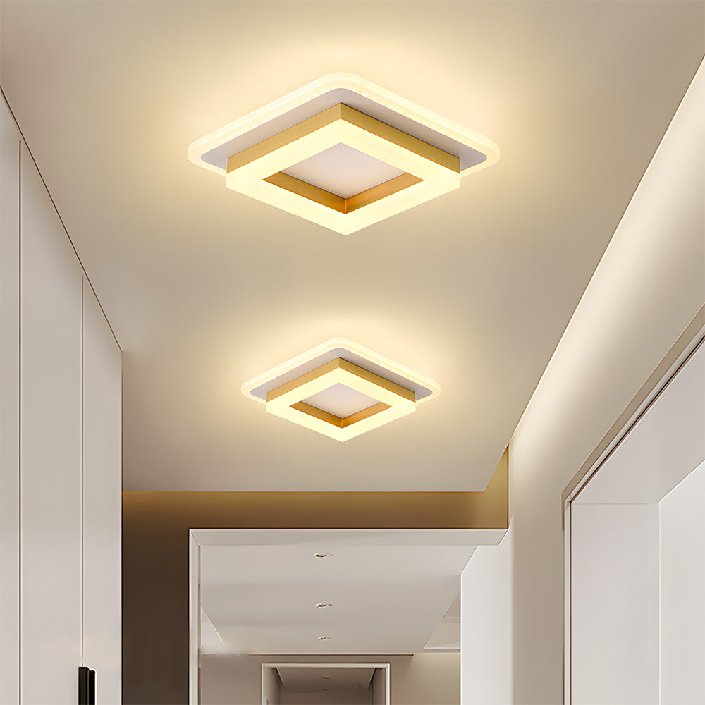 Two gold layered square flush mount serq ceiling lights casting a warm glow in a modern minimalist hallway