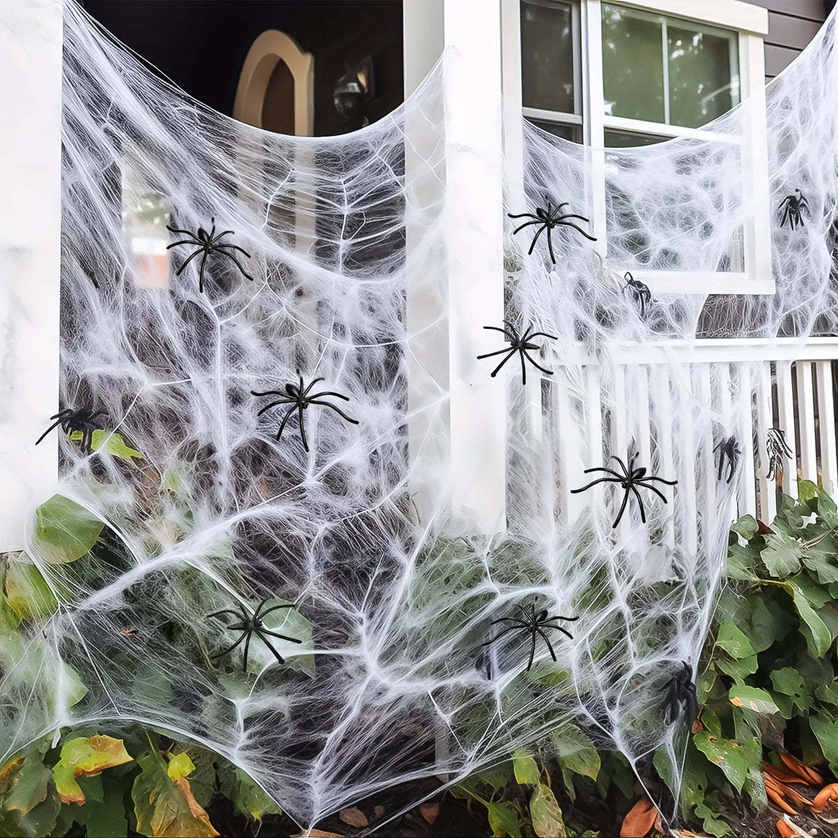 Silkshroud stretch cobweb covering porch columns, a window and railing with spiders scattered throughout