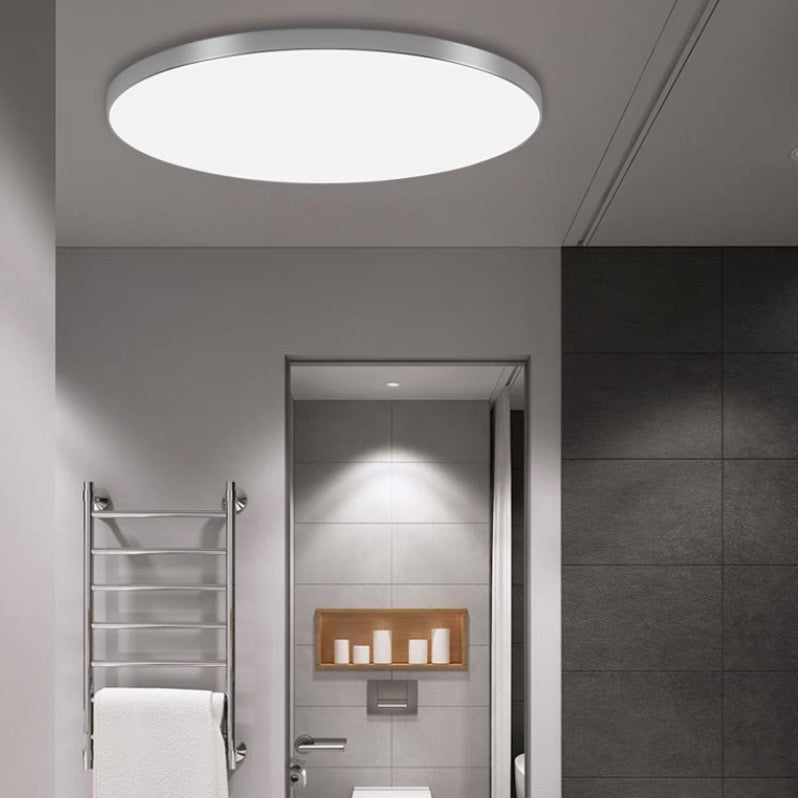 Silver flat panel LED flush mount light installed in a minimalist grey corridor
