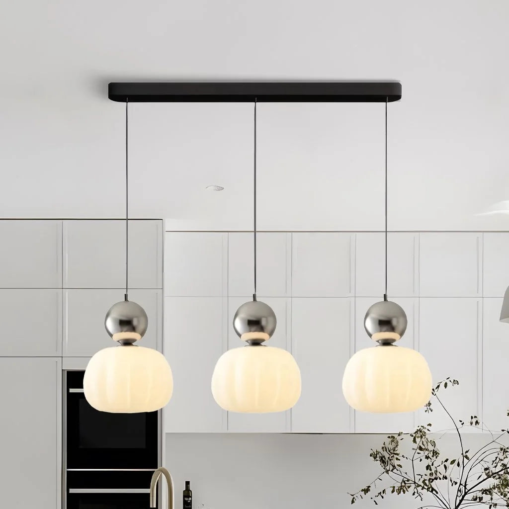 Silver three-head linear chandelier providing sophisticated lighting in a contemporary kitchen