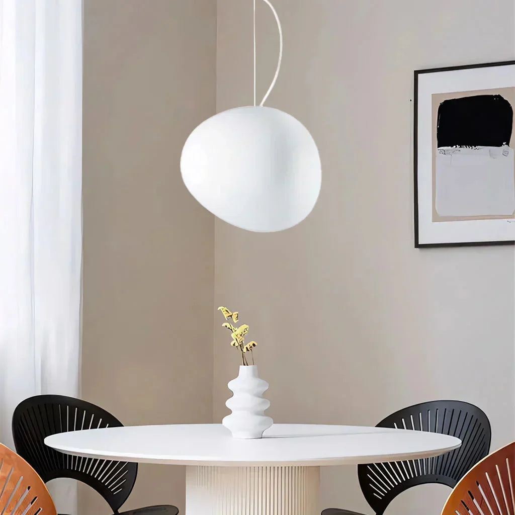 Single frosted glass stone pendant light suspended over a round dining table in a bright room