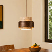 Single Japandi travertine stone pendant light with a dark wood band hanging over a dining table