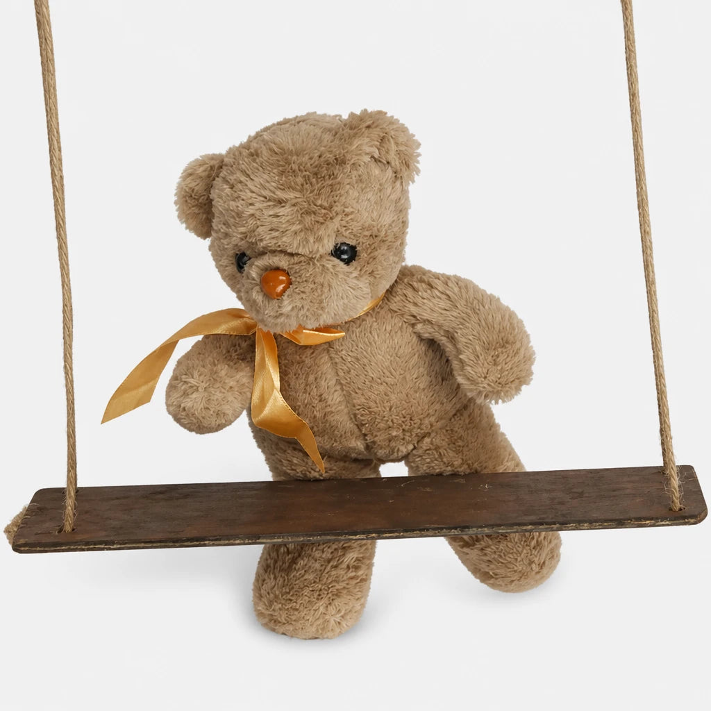 Close-up detail of the teddy bear accessory with gold ribbon on Skulke's wooden swing