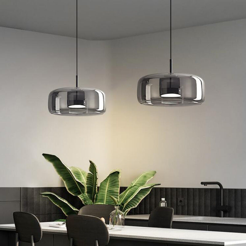 Two wide smoke grey glass pendant lights complementing a sophisticated, dark-toned kitchen island