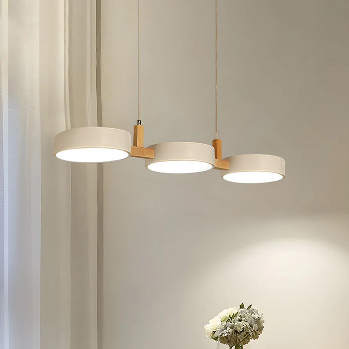 Solid white 3-head drum pendant light providing ambient light over a round dining table