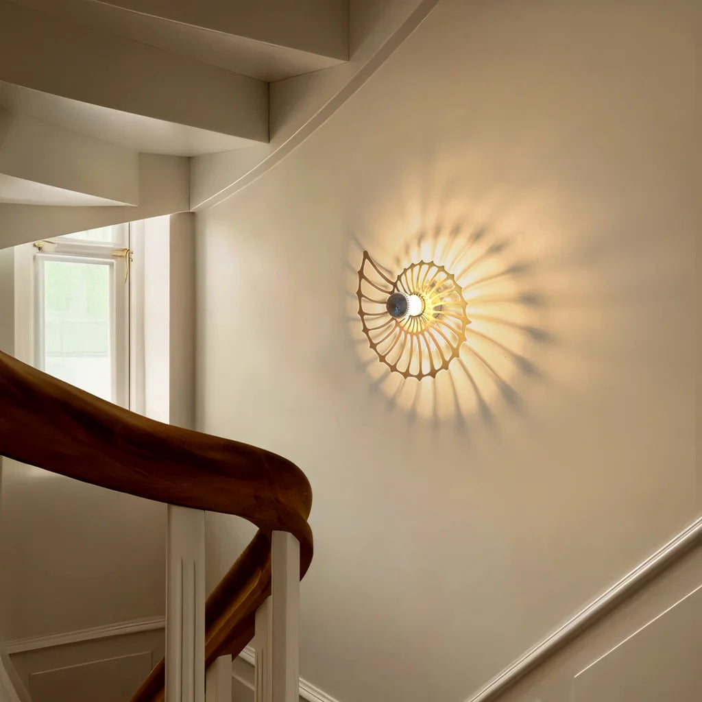 spiral LED sconce casting beautiful light rays and shadows on a curved indoor stairwell