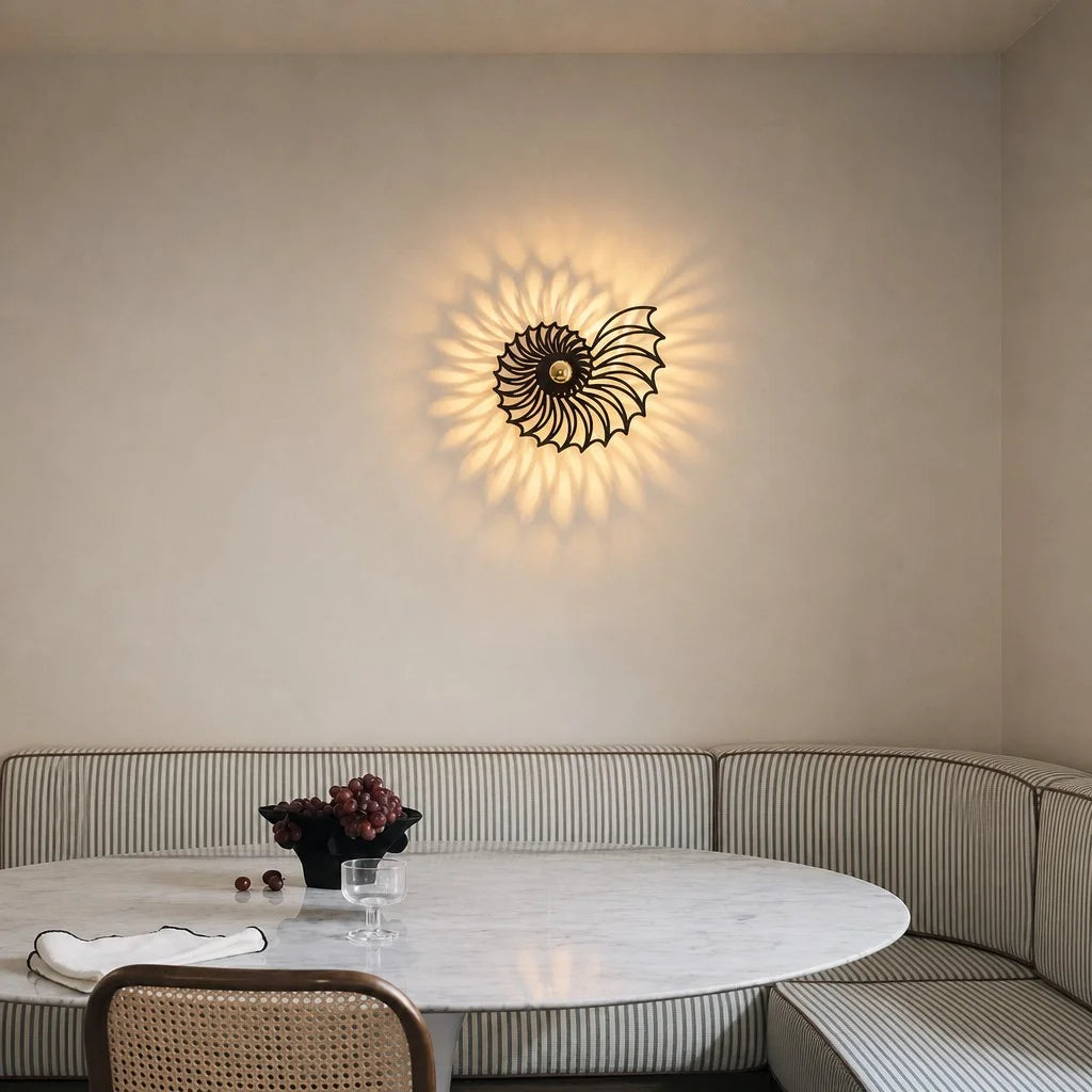 Spiral shadow wall light installed in a stylish dining nook with a marble table and striped seating
