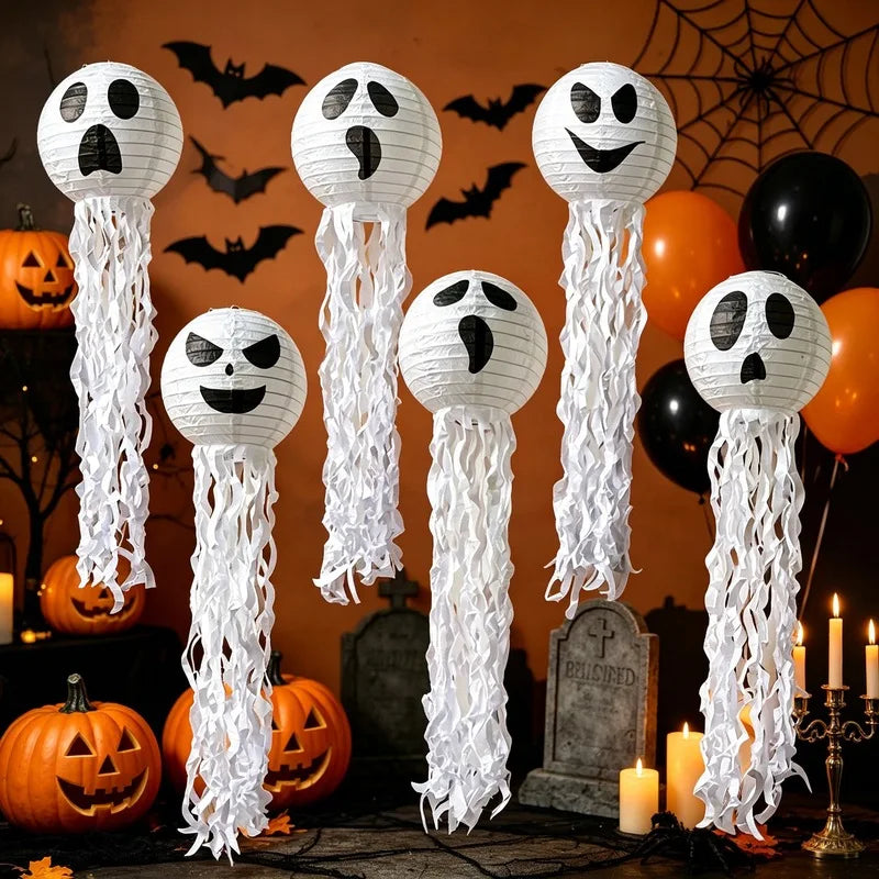 Spookballs ghost paper lanterns hanging in front of a graveyard and spiderweb Halloween party backdrop with balloons