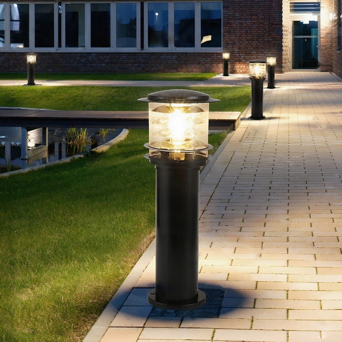 tall black LED path light standing elegantly between a paved walkway and a green lawn