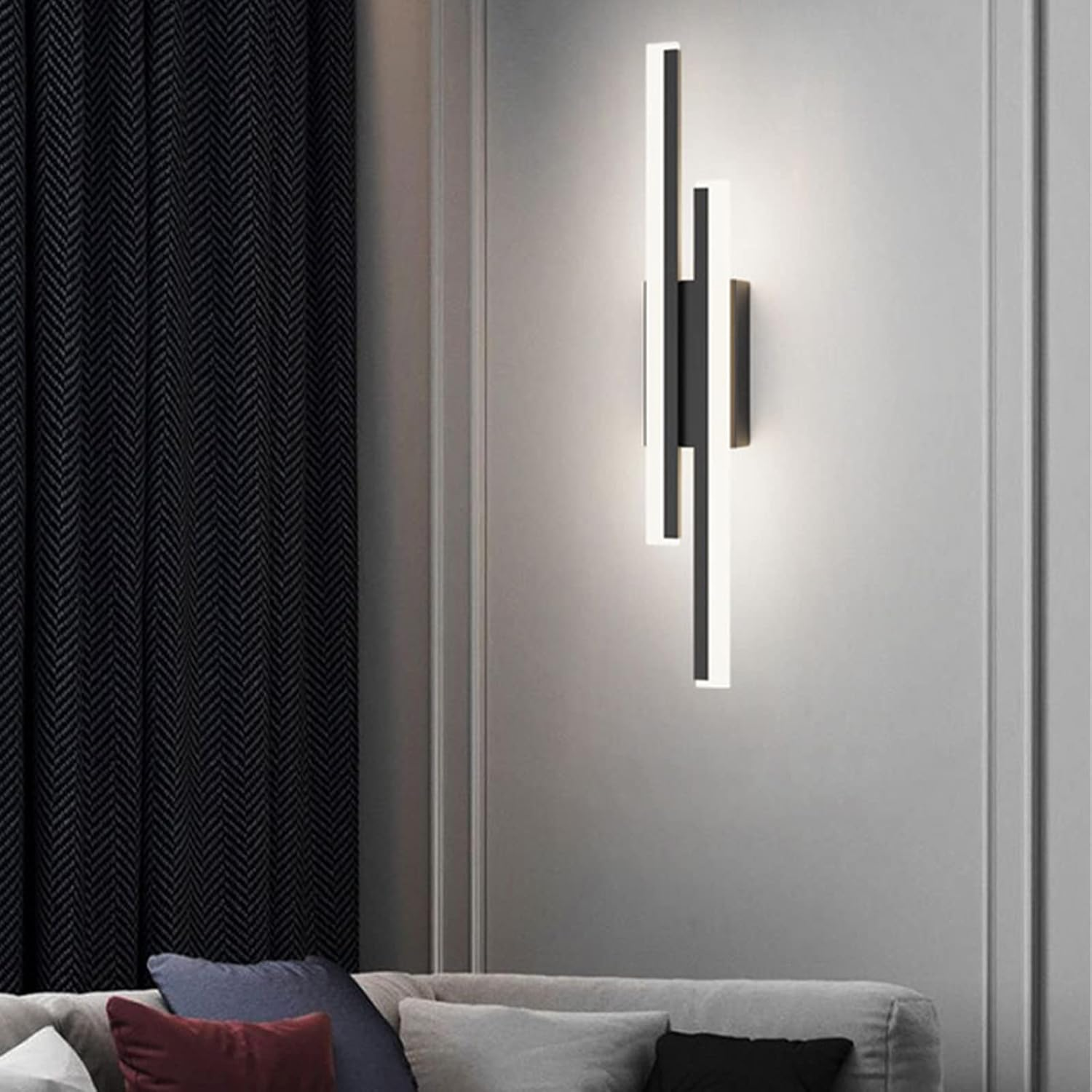 Tall black linear wall sconce providing soft ambient lighting in a modern living room setting