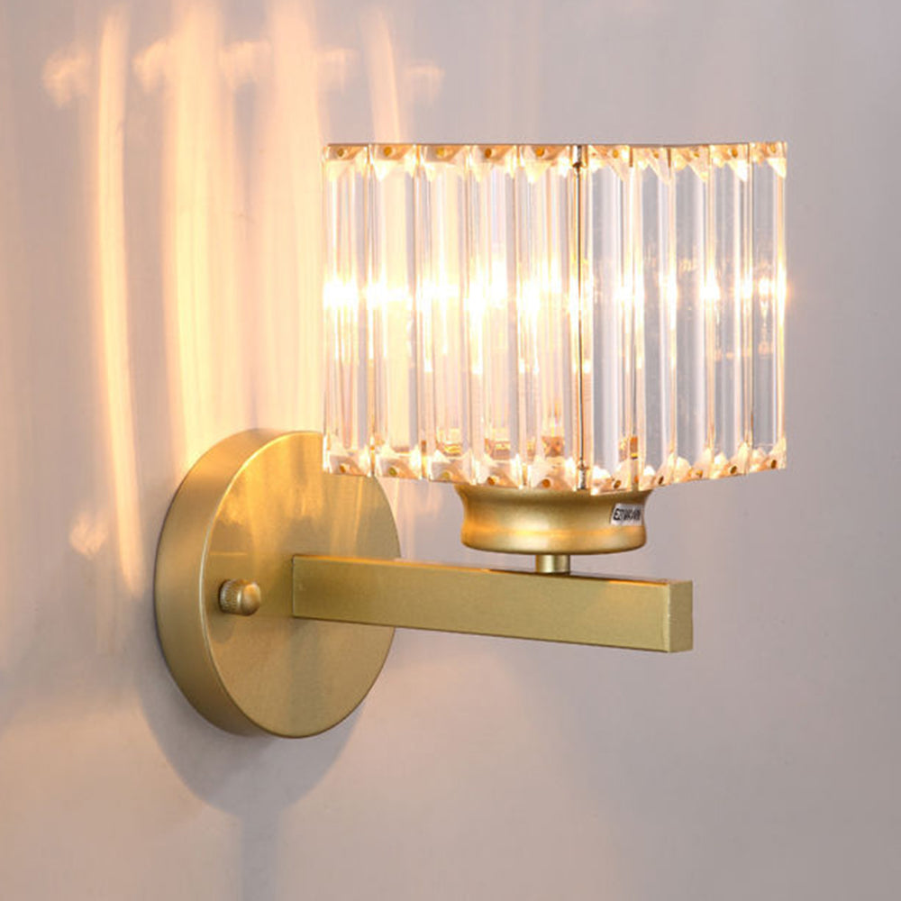 Side view of the glowing teja gold square crystal wall sconce casting warm ambient light on a wall