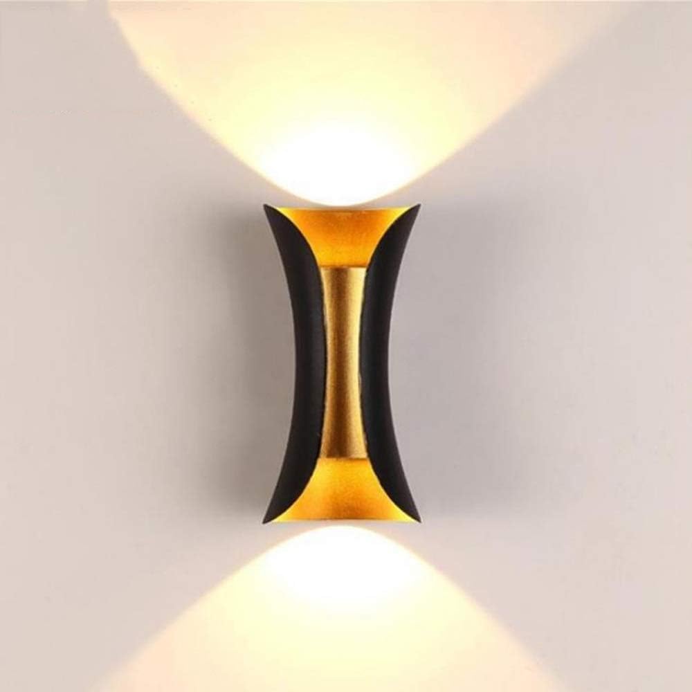 Illuminated black and gold teka LED up and down sconce against a neutral, warm background