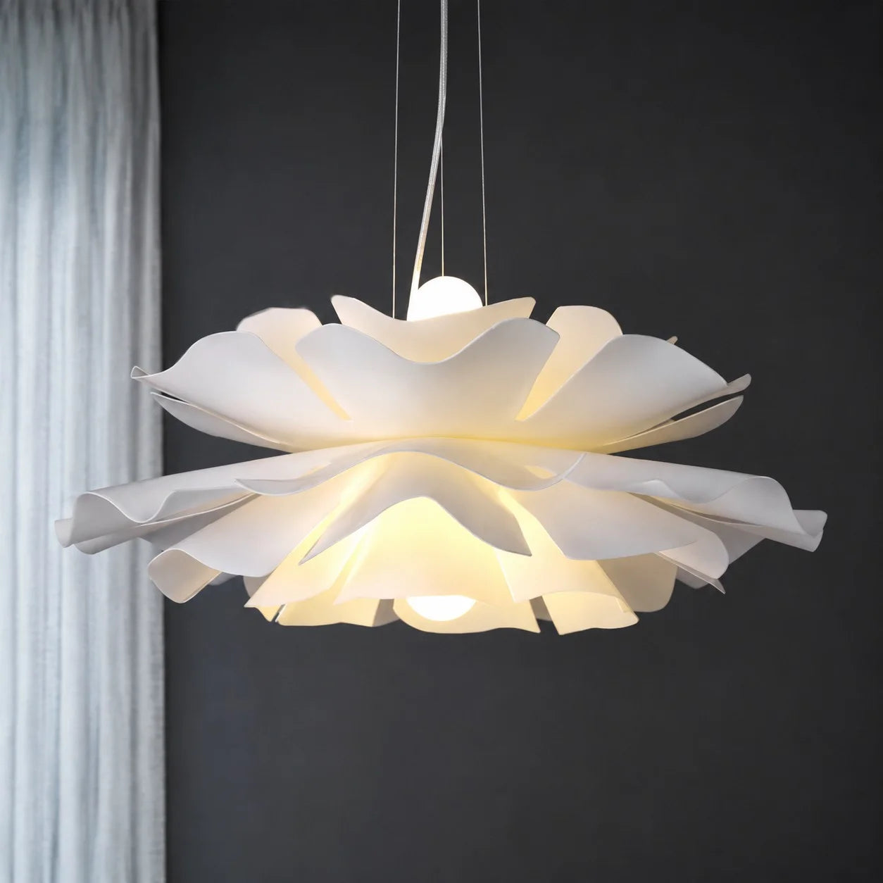 Modern telba white Nordic lotus flower pendant light glowing warmly against a dark background