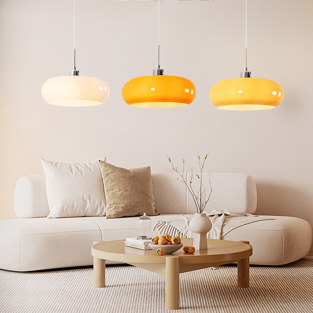Three multicolour glass dome pendants hanging in a stylish modern lounge area with a low cream sofa