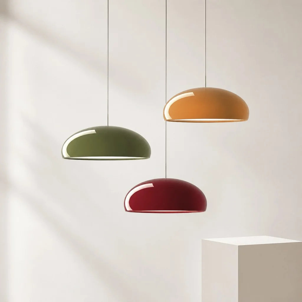 Three multicoloured Bauhaus pendants in green, orange, and red hanging at staggered heights