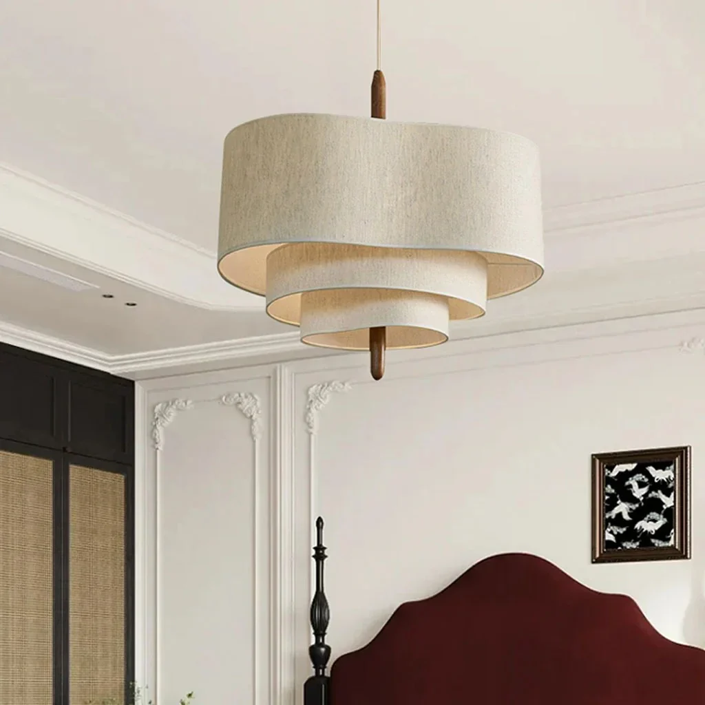 Tiered fabric chandelier acting as an elegant, tranquil focal point in a modern bedroom with a burgundy headboard