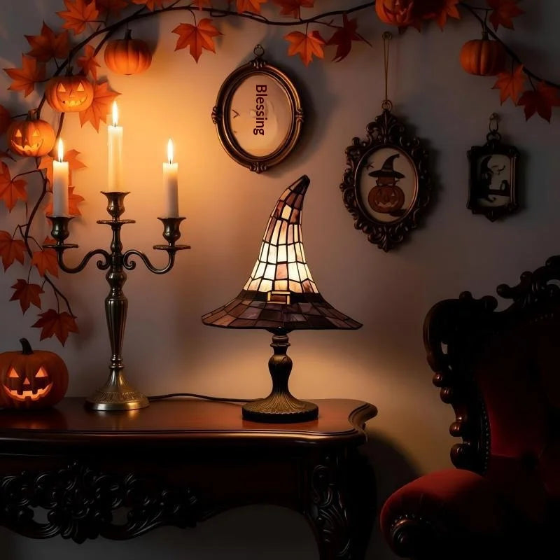 Tiffspell stained glass witch hat table lamp lit on a table with Halloween wall decor