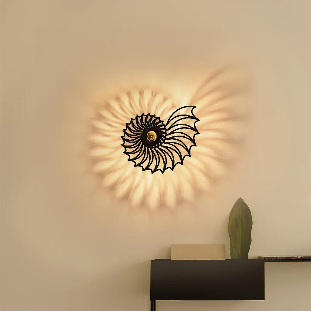 Modern black tilo Nautilus shell LED wall sconce casting a spiralling shadow pattern above a minimalist console table