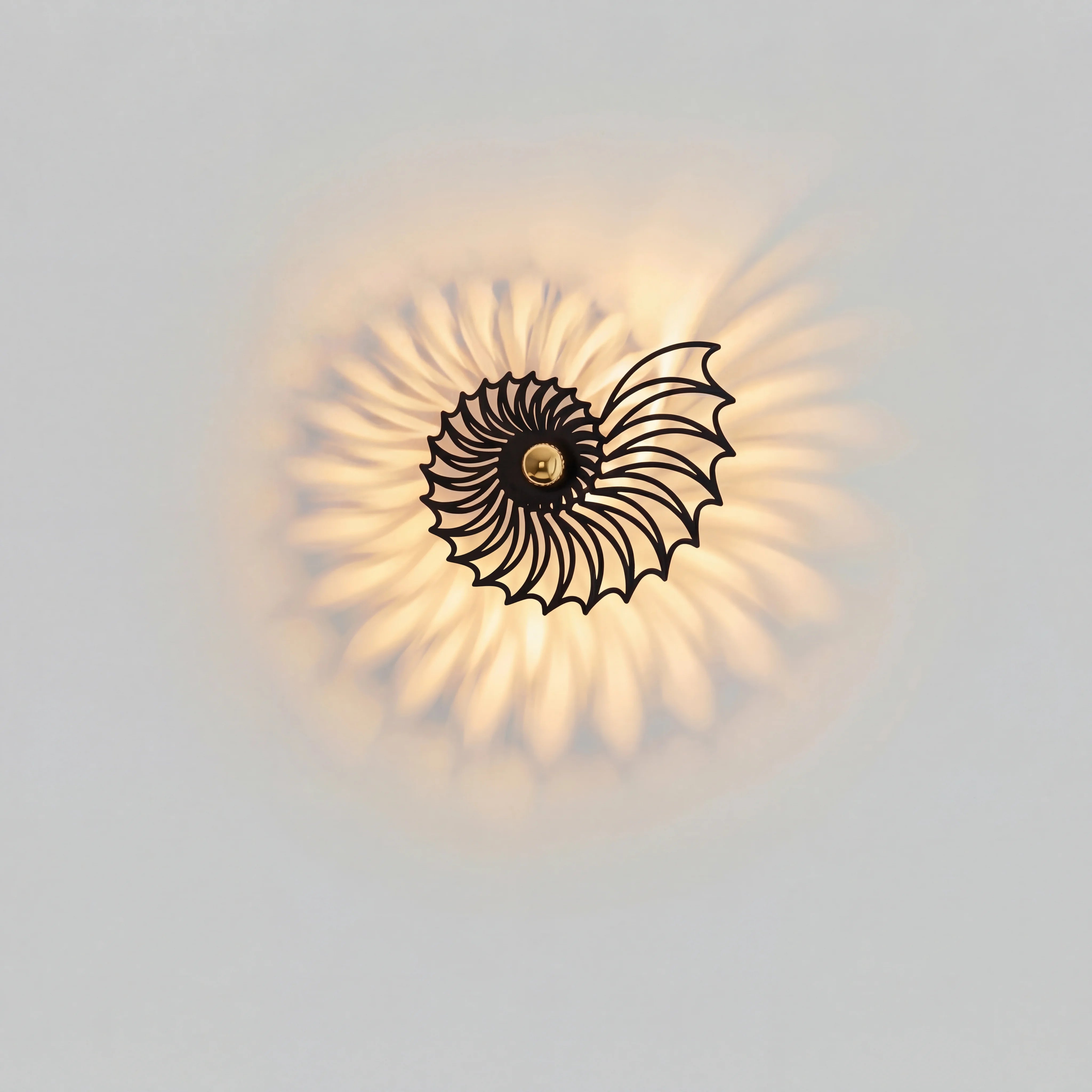 Front view of the illuminated tilo black spiral wall lamp showcasing its intricate geometric metal cutouts