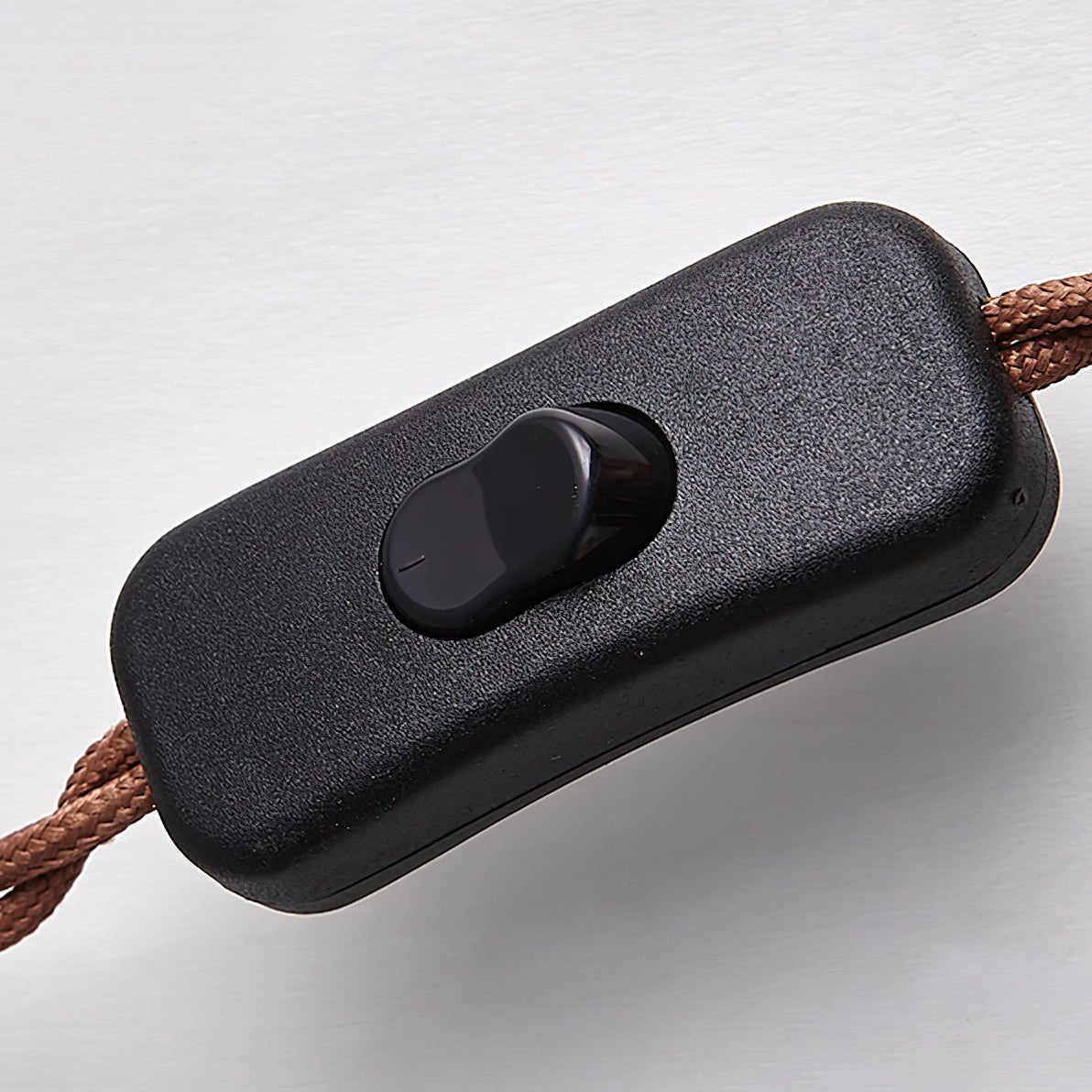Close-up of the black inline on/off push-button switch attached to the premium brown braided power cable