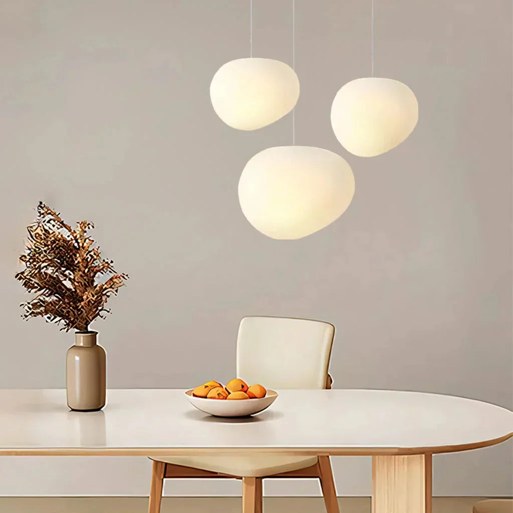 Staggered cluster of frosted glass pebble tupel pendant lights creating a striking dining room chandelier