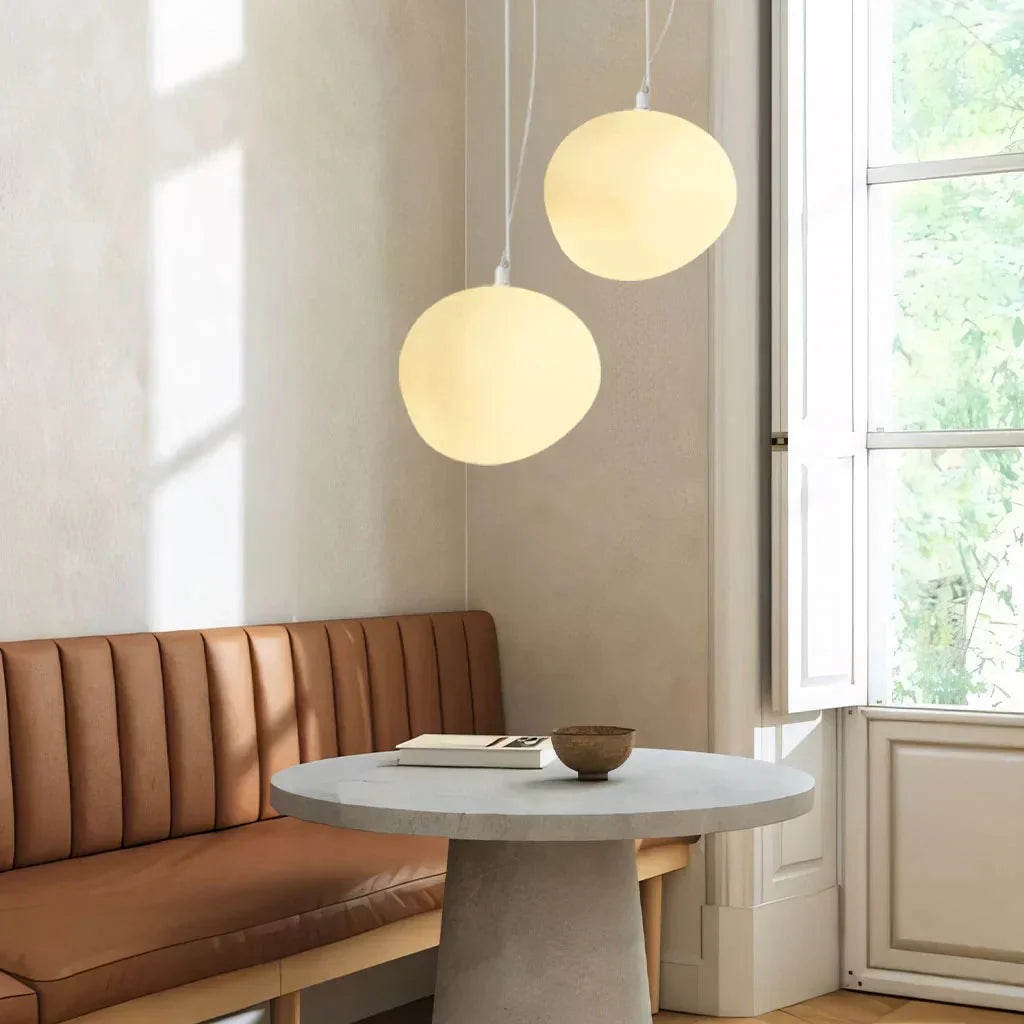 Pair of organic glass pebble pendants providing warm ambient lighting over a dining banquette