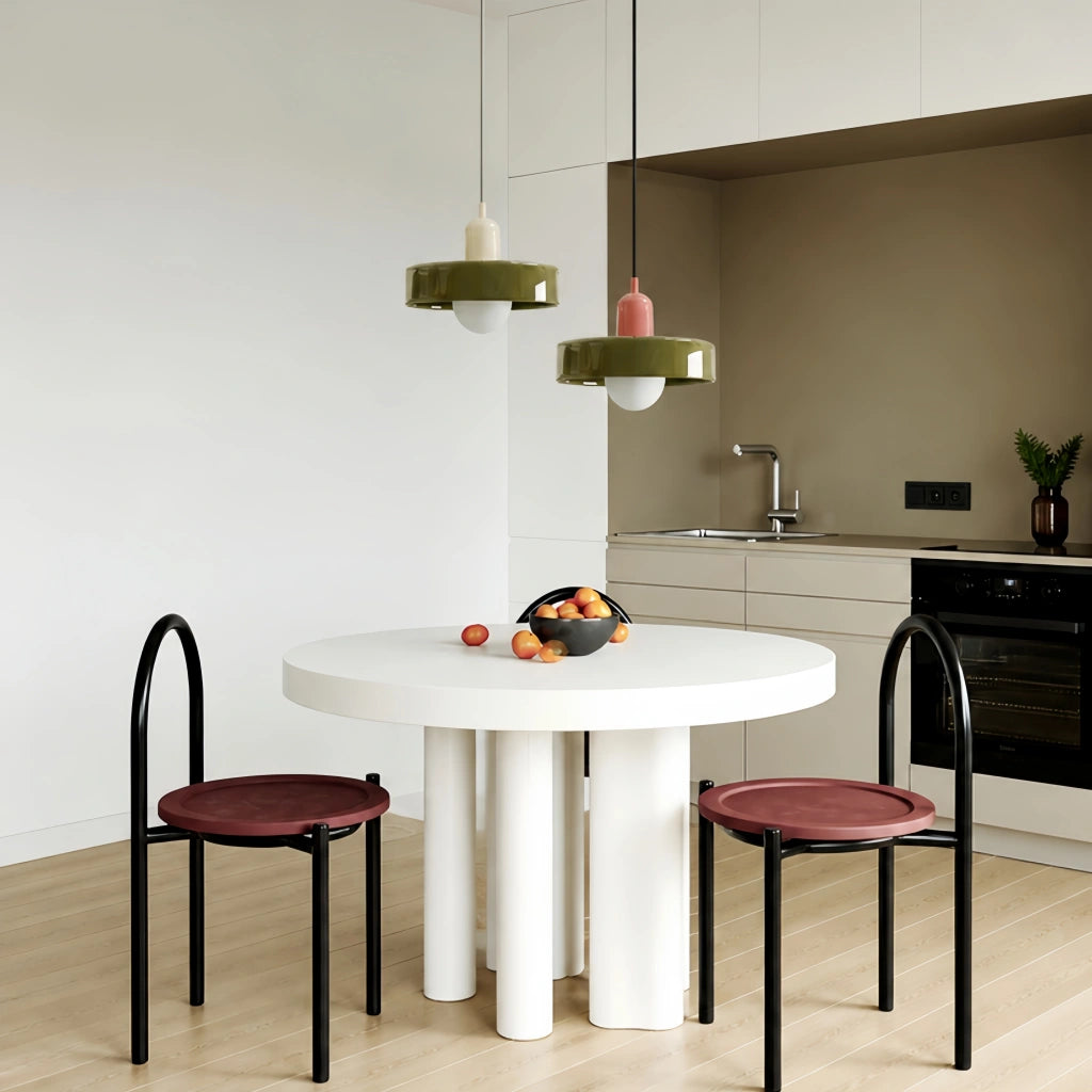 Two retro colour-block pendant lights in green suspended over a modern round dining table