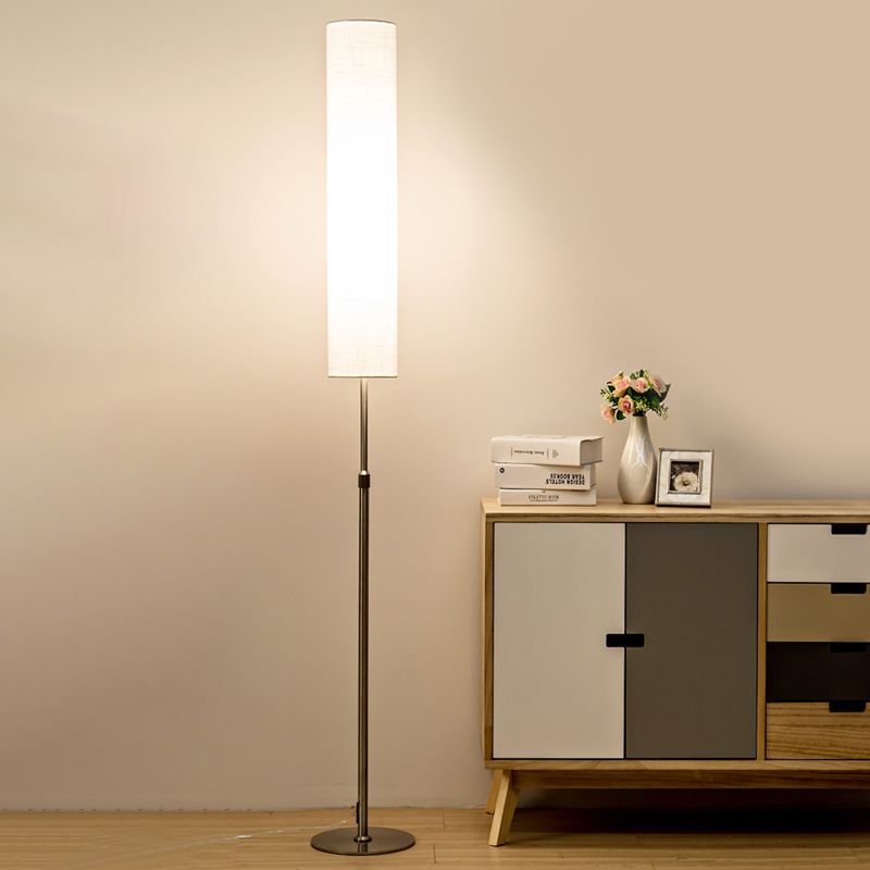 Modern cylindrical fabric vatel floor lamp providing warm ambient light next to a contemporary sideboard