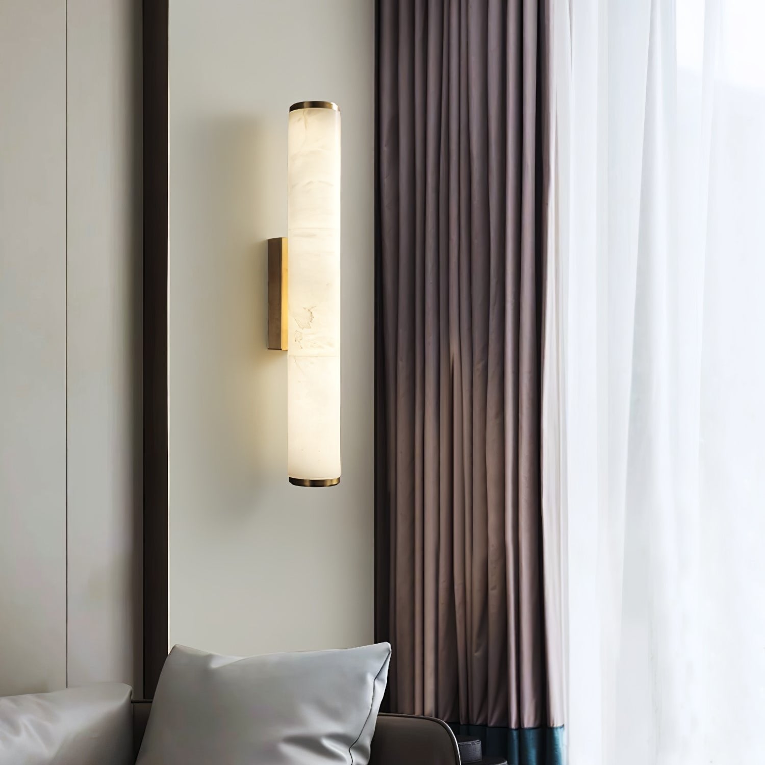 Vertical marble wall lamp providing elegant ambient lighting next to a bright window with curtains