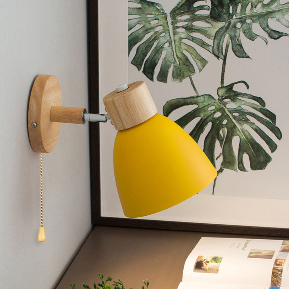 Vibrant yellow macaron vexol wall lamp with a pull cord illuminating a cosy reading nook shelf