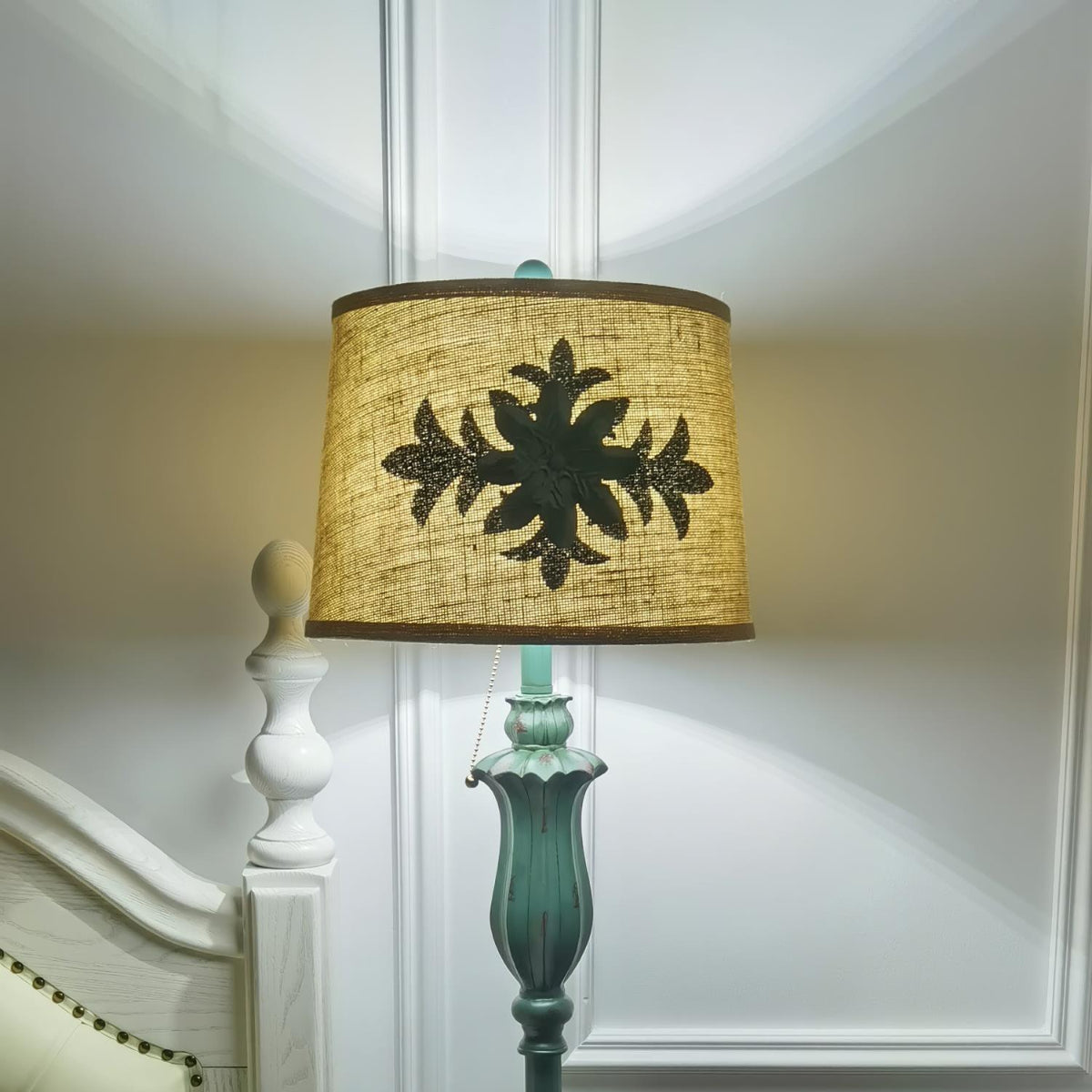 Close-up detail of the illuminated vintage fabric lampshade and sculpted green resin column