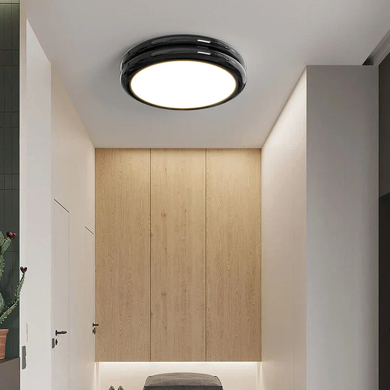 Black retro flush mount vyter ceiling light providing bright illumination in a modern wooden hallway